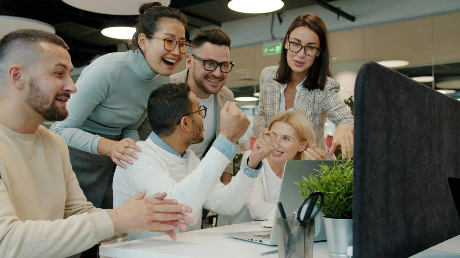 Young team celebrating together around a desk